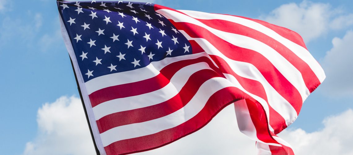 low angle view of stars and stripes on american flag against blue sky