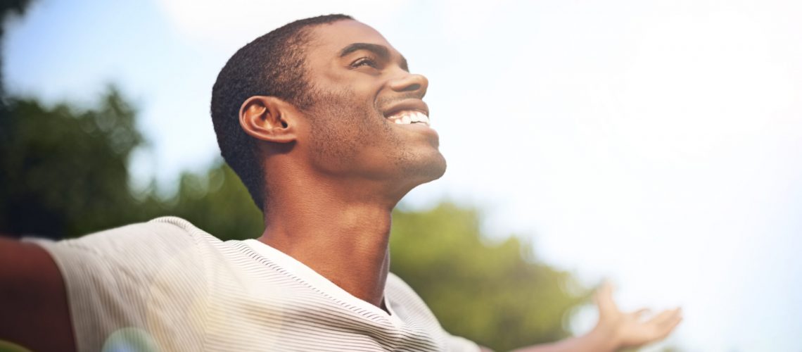 Shot of a man standing outside with his arms outstretched in delight.